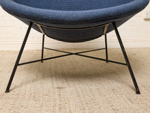 Load image into Gallery viewer, Image 14 of 17: A close-up of a modern barrel chair with a textured blue fabric seat and black metal legs, positioned on a beige woven rug against a white brick wall.
