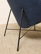 Load image into Gallery viewer, Image 13 of 17: Close-up of a modern chair with a textured navy blue upholstered seat and black metal legs, shown on a woven beige rug against a white brick wall.
