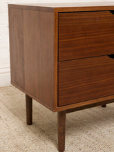 Load image into Gallery viewer, Image 9 of 16: Vintage mid-century modern wooden nightstand featuring two stacked drawers with recessed crescent-shaped pulls, warm walnut-tone wood grain, rectangular cabinet frame, and four slender tapered legs.

