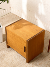 Load image into Gallery viewer, Image 6 of 17: Vintage mid-century modern rectangular wooden cabinet featuring a honey-brown wood grain finish, single flat-panel door, dark vertical metal pull, and contrasting darker wood trim along both sides.
