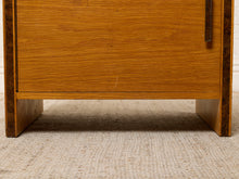 Load image into Gallery viewer, Image 14 of 17: Vintage mid-century modern rectangular wooden cabinet featuring a honey-brown wood grain finish, single flat-panel door, dark vertical metal pull, and contrasting darker wood trim along both sides.
