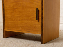 Load image into Gallery viewer, Image 15 of 17: Vintage mid-century modern rectangular wooden cabinet featuring a honey-brown wood grain finish, single flat-panel door, dark vertical metal pull, and contrasting darker wood trim along both sides.
