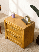 Load image into Gallery viewer, Image 6 of 21: Vintage honey oak nightstand featuring two drawers, natural wood grain, rounded faux-bamboo trim, and antique brass-tone horizontal handles, available as a pair.
