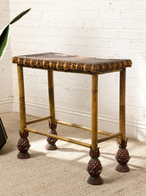 Load image into Gallery viewer, Image 5 of 20: Antique rectangular bamboo-style accent table featuring a dark brown embossed decorative tabletop, ornate gold-tone floral trim, slender golden bamboo legs, crossbar supports, and sculptural pineapple-like feet.
