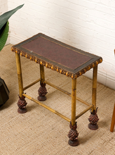 Load image into Gallery viewer, Image 6 of 20: Antique rectangular bamboo-style accent table featuring a dark brown embossed decorative tabletop, ornate gold-tone floral trim, slender golden bamboo legs, crossbar supports, and sculptural pineapple-like feet.
