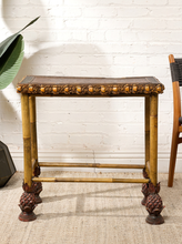 Load image into Gallery viewer, Image 4 of 20: Antique rectangular bamboo-style accent table featuring a dark brown embossed decorative tabletop, ornate gold-tone floral trim, slender golden bamboo legs, crossbar supports, and sculptural pineapple-like feet.
