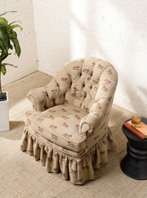 Load image into Gallery viewer, Image 3 of 18: Vintage upholstered barrel chair featuring beige textured fabric with repeating brown lion motifs, a deeply tufted rounded backrest, padded rolled arms, thick seat cushion, and matching ruffled skirt.
