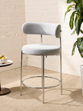 Load image into Gallery viewer, Image 5 of 18: Modern upholstered bar stool featuring a curved beige textured fabric backrest, cushioned seat, slender chrome-finished metal legs, and circular metal footrest. Sold as a pair.
