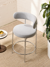 Load image into Gallery viewer, Image 6 of 18: Modern upholstered bar stool featuring a curved beige textured fabric backrest, cushioned seat, slender chrome-finished metal legs, and circular metal footrest. Sold as a pair.
