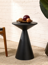Load image into Gallery viewer, Image 2 of 14: Modern round black side table featuring a smooth circular tabletop, matte black finish, and sculptural tapered cone-shaped pedestal base with subtle surface marks.
