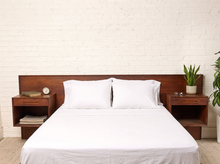 Load image into Gallery viewer, Image 1 of 22: Vintage Danish modern teak headboard featuring a long rectangular wood panel with rich reddish-brown grain and two adjustable open-box nightstands positioned near either end, compatible with queen or king beds.
