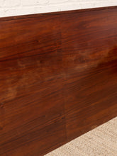 Load image into Gallery viewer, Image 10 of 22: Close-up of a dark reddish-brown wooden surface, likely a cabinet or panel, with visible wood grain and a light beige textured rug below.
