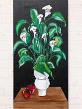 Load image into Gallery viewer, Image 2 of 8: Floral still life painting featuring white calla lilies with yellow centers, large sweeping green leaves, a white vase, and two red peppers on a brown tabletop against a solid black background.
