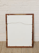 Load image into Gallery viewer, Image 8 of 8: A rectangular wooden picture frame with a white backing board and a visible hanging wire, leaning against a white painted brick wall on a woven rug.
