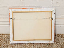 Load image into Gallery viewer, Image 8 of 8: The back of a rectangular framed art piece, showing a distressed white wooden frame, a light wood inner border, and hanging wire hardware against a white brick wall and woven rug.
