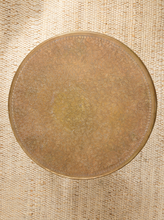 Load image into Gallery viewer, Image 4 of 13: Vintage round brass-tone foot warmer featuring a circular top with intricate floral and scrollwork engravings, a raised rounded rim, warm aged patina, and three short turned metal legs.
