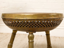Load image into Gallery viewer, Image 9 of 13: Vintage round brass-tone foot warmer featuring a circular top with intricate floral and scrollwork engravings, a raised rounded rim, warm aged patina, and three short turned metal legs.
