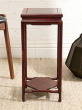 Load image into Gallery viewer, Image 4 of 16: A dark reddish-brown wooden side table with a square top, open lower shelf, and four legs, shown in a styled room setting with a white brick wall and woven rug.
