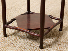 Load image into Gallery viewer, Image 13 of 16: Close-up of a dark reddish-brown wooden stand or table base with a hexagonal center panel and curved support legs, photographed on a woven beige rug.

