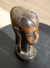 Load image into Gallery viewer, Image 5 of 13: A carved wooden sculpture of a stylized head with a circular base, photographed on a dark round surface with a softly blurred beige background.
