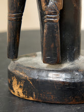 Load image into Gallery viewer, Image 11 of 13: Close-up of a carved wooden figurine or sculpture base, showing dark stained wood with worn tan areas and a circular pedestal foundation.
