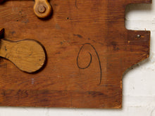 Load image into Gallery viewer, Image 7 of 9: A close-up of a rustic wooden board with a carved wooden handle or knob, showing visible grain, wear, and a black painted number nine on the surface, set against a white brick wall background.
