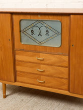 Load image into Gallery viewer, Image 7 of 27: Mid-century modern wooden sideboard cabinet with three drawers, a glass-front upper cabinet featuring a decorative floral design, and brass handles.
