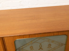 Load image into Gallery viewer, Image 10 of 27: Close-up of a mid-century modern wooden cabinet with a warm medium-brown wood grain finish and a frosted glass door featuring a gold geometric pattern.

