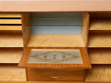 Load image into Gallery viewer, Image 23 of 27: A close-up of a wooden storage cabinet or desk with a pull-out drawer panel. The panel has a decorative geometric inlay on a frosted glass insert, and the cabinet interior features shelves and a glass shelf.

