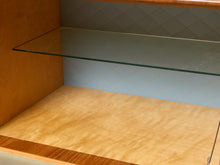 Load image into Gallery viewer, Image 25 of 27: A close-up view of a wooden cabinet interior with a clear glass shelf and a light natural wood bottom panel.
