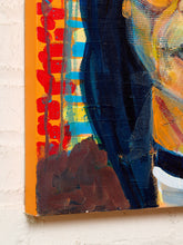 Load image into Gallery viewer, Image 5 of 8: A close-up of an abstract canvas painting mounted on a white brick wall. The artwork features bold, textured brushstrokes in dark navy blue, bright orange, red, yellow, and brown.

