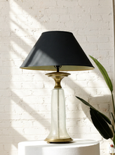 Load image into Gallery viewer, Image 1 of 18: Vintage table lamp featuring a tall tapered champagne seeded glass base with brass-tone neck and foot, topped with a wide charcoal gray tapered fabric lampshade.
