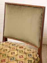 Load image into Gallery viewer, Image 7 of 15: A close-up of an upholstered wooden chair with a square backrest in muted sage green velvet and a patterned seat cushion in beige, red, and blue.
