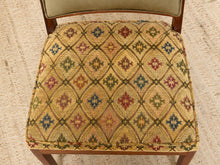 Load image into Gallery viewer, Image 10 of 15: A close-up of an upholstered chair seat with a woven diamond pattern in beige, red, blue, green, and brown, with wooden legs and a light upholstered backrest visible.
