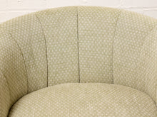Load image into Gallery viewer, Image 9 of 16: Close-up of a curved upholstered armchair or sofa section with a light beige fabric covered in a small repeating geometric pattern, set against a white painted brick wall.
