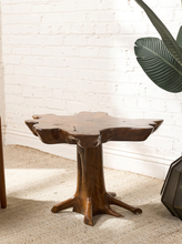 Load image into Gallery viewer, Image 2 of 16: Sculptural wood coffee table featuring a thick, irregularly shaped freeform tabletop with a warm brown finish, organic curved edges, and a branching tree root-style pedestal base.
