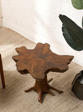 Load image into Gallery viewer, Image 1 of 16: Sculptural wood coffee table featuring a thick, irregularly shaped freeform tabletop with a warm brown finish, organic curved edges, and a branching tree root-style pedestal base.
