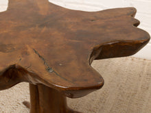 Load image into Gallery viewer, Image 7 of 16: Close-up of a rustic wooden stool with a hand-shaped organic table top and a thick round pedestal base, showing a warm medium-brown finish with natural wood grain and a small crack.
