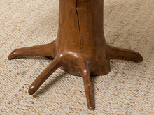Load image into Gallery viewer, Image 16 of 16: Close-up of a carved wooden base with five curved legs resembling tree roots, resting on a textured beige woven rug.
