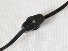 Load image into Gallery viewer, Image 21 of 22: A close-up of a black inline cable connector with a textured plastic housing and a small gold screw, shown on a white textured background.
