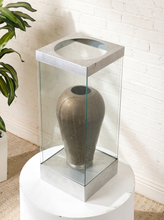 Load image into Gallery viewer, Image 3 of 18: Vintage dark brown sculptural vase with rounded shoulders, a narrow circular opening, tapered body, and weathered surface, displayed inside a tall rectangular glass case with brushed silver-tone metal top and base.
