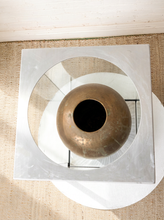 Load image into Gallery viewer, Image 5 of 18: Vintage dark brown sculptural vase with rounded shoulders, a narrow circular opening, tapered body, and weathered surface, displayed inside a tall rectangular glass case with brushed silver-tone metal top and base.
