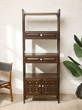 Load image into Gallery viewer, Image 4 of 25: Vintage dark wood étagère bookshelf featuring three open display shelves, two drawers with raised rectangular panel details, a lower double-door cabinet with geometric square panels, and round cream-colored knobs.

