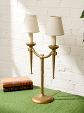 Load image into Gallery viewer, Image 11 of 21: Pair of vintage gold-tone metal table lamps, each featuring two gracefully curved arms, candle-style light fittings, smooth ivory tapered fabric shades, a slender central stem, and a rounded pedestal base.
