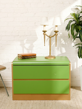 Load image into Gallery viewer, Image 1 of 16: Vintage 1970s postmodern nightstand featuring bright lime-green drawer fronts, contrasting gold-tone trim, a gently rounded top, and two handle-free drawers.

