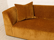 Load image into Gallery viewer, Image 9 of 16: A close-up of a mustard yellow velvet sofa with a matching square throw pillow, set against a white brick wall and light-colored rug.
