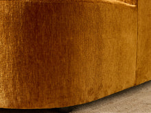 Load image into Gallery viewer, Image 16 of 16: Close-up of a mustard yellow textured fabric upholstered furniture piece, showing the woven material and curved lower edge above a neutral floor surface.
