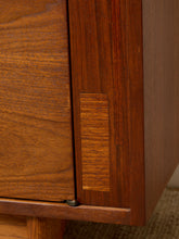 Load image into Gallery viewer, Image 15 of 24: Close-up of a mid-century modern wooden cabinet or sideboard, highlighting the rich warm brown wood grain, a recessed panel, and a metal hinge screw.
