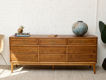 Load image into Gallery viewer, Image 1 of 21: Vintage mid-century modern nine-drawer walnut dresser by Dixie Furniture Co. featuring three upper drawers with brass-tone handles, six lower drawers with integrated pulls, warm brown wood grain, and slender tapered legs.
