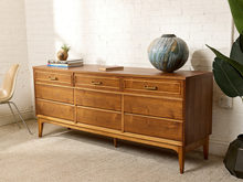 Load image into Gallery viewer, Image 2 of 21: Vintage mid-century modern nine-drawer walnut dresser by Dixie Furniture Co. featuring three upper drawers with brass-tone handles, six lower drawers with integrated pulls, warm brown wood grain, and slender tapered legs.
